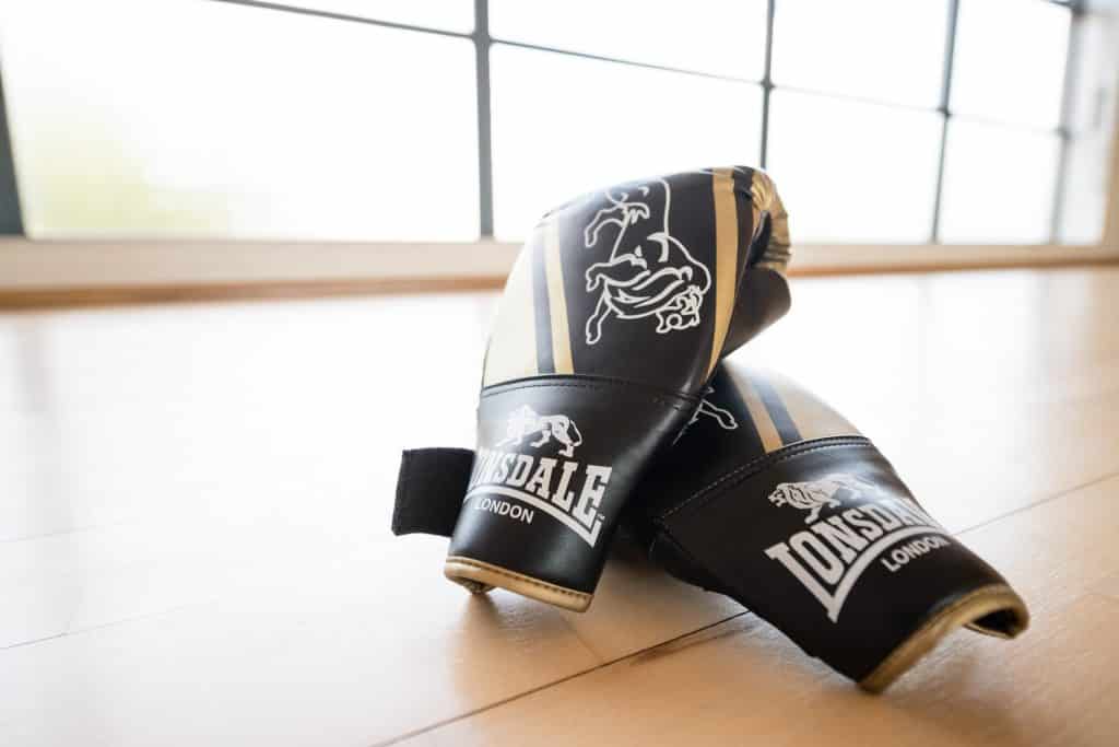 A pair of boxing gloves on the floor of a bright dance studio